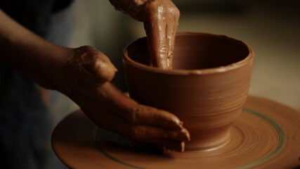 Fototapeta na wymiar Girl shaping clay product in pottery. Woman sculpting clay pot in workshop