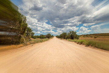Rural dirt road with motion blur perspective and dramatic clouds in the sky.