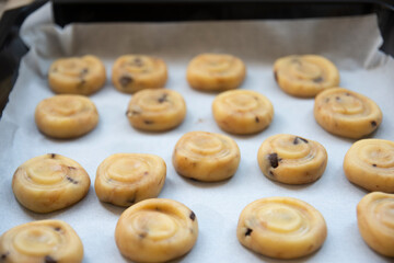 shaped, ready-to-bake dough close-up on tray. Adult woman bakes delicious and crunchy cookies in pandemic