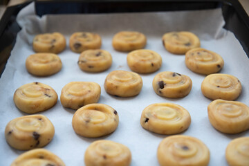 shaped, ready-to-bake dough close-up on tray. Adult woman bakes delicious and crunchy cookies in pandemic