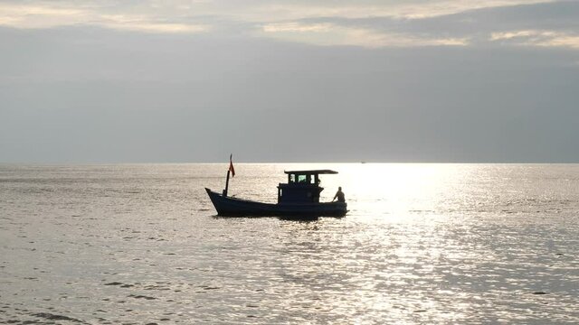A fishing boat floating in the tranquil sea on a calm sunny afternoon.