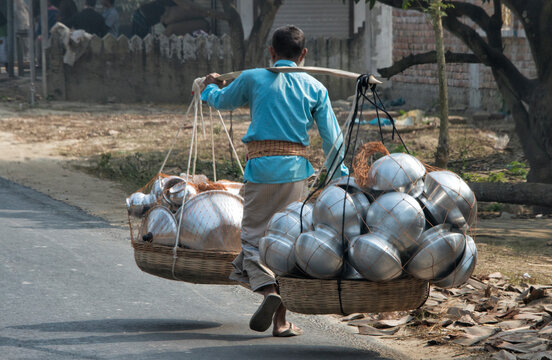 Man carrying baskets of pots with a shoulder pole, Rajshahi Division, Bangladesh