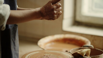 Lady getting ready to make product in studio. Woman sculpting clay in pottery