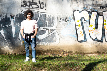 Young Man Posing at Graffiti Wall Outside