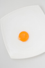Detalle de la yema de huevo sin cáscara sobre un plato con fondo blanco
