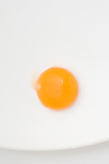 Detalle de la yema de huevo sin cáscara sobre un plato con fondo blanco