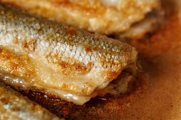 Fresh smelt, fried in hot oil in a frying pan for a healthy lunch close up. Smelt - fish that smells like cucumbers. concept of fried unhealthy food on oil