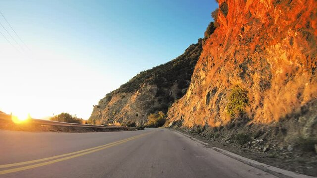 Car travel gopro point of view across mediterranean coastal nature, rocky steep slopes and golden shining sunlight, remote asphalt road POV drive