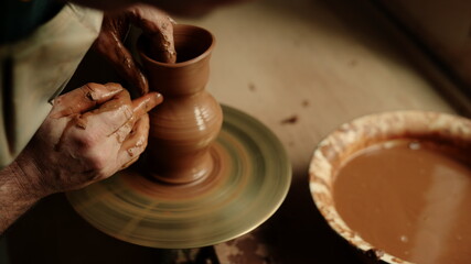 Ceramist producing clay jar in pottery. Unrecognized man working with wet clay 