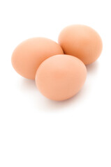 Tres huevos morenos sobre fondo blanco