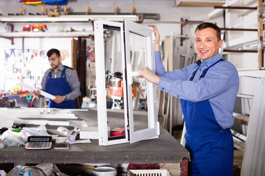 Two Diligent Smiling Careful Workmen Inspecting PVC Manufacturing Output In Workshop