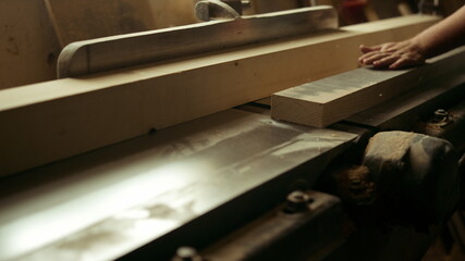 Unknown carpenter cutting wood in workshop. Man preparing plank in studio