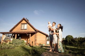 Fototapeta premium happy family stand near their new home, joint construction of a house
