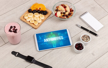 ANTIBIOTICS concept in tablet with fruits, top view