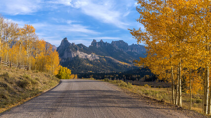 Autumn Mountain Road - An Autumn evening view of a backcountry road extending towards rugged mountain ridges. Owl Creek Pass Road, Cimarron-Ridgway, Colorado, USA.