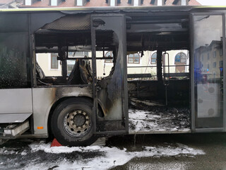 Burnt public traffic bus is seen on the street after caught in fire during travel and extinguished by firefighters.
