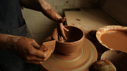 Unknown girl working with wet clay in pottery. Woman sculpting clay pot
