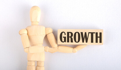 Wooden man shows with a hand to block with text GROWTH