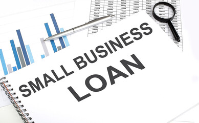 In the notebook, the text SMALL BUSINESS LOAN , next to magnifier and a pen, the background is graphics.