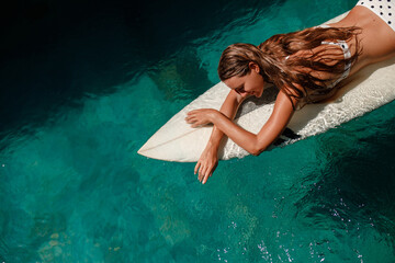 Aerial view of a woman on white surfboard in the swiming pool