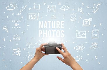 Fototapeta na wymiar Hand taking picture with digital camera and NATURE PHOTOS inscription, camera settings concept