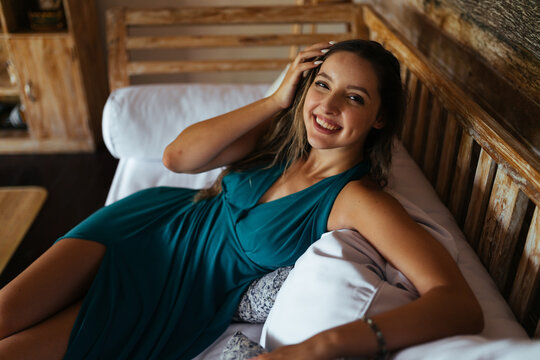 among the pillows on the bed in the interior of the tree sits a laughing girl. High quality photo