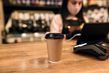 Buying a cup of coffee in a cafe, barista, NFC terminal. Blurred background