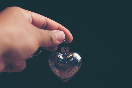 Cropped Hand Holding Heart Shape Locket Against Black Background