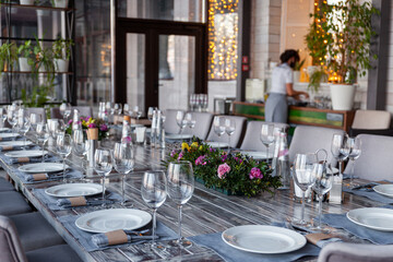 Modern veranda restaurant interior, flowers, banquet setting, glasses, plates