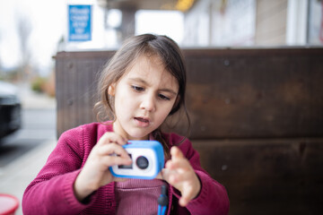 Little girl holding a small camera for kids