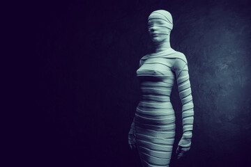 A female mannequin wrapped in an elastic bandage on a dark background.