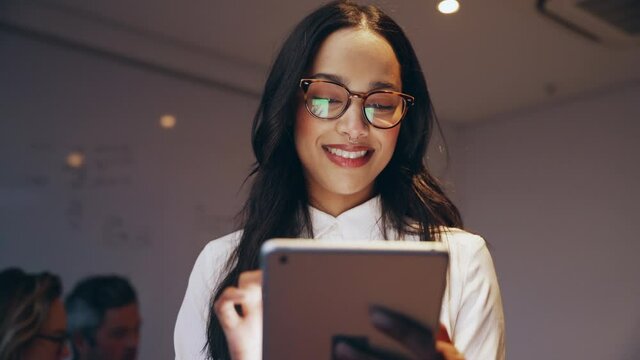 Mixed race business woman typing on iPad emailing assignment to manager happy for meeting deadline of project