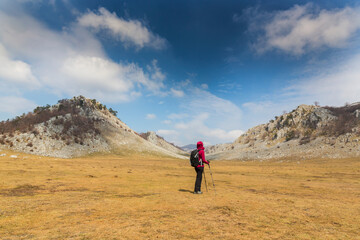 Obraz premium Beautiful scenery in the mountains with sharp limestome rocks, hiking path and April sky and showers, with cumulus clouds
