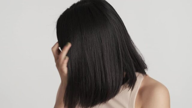 Beautiful charming Asian girl preening on camera showing new bob haircut isolated on white background