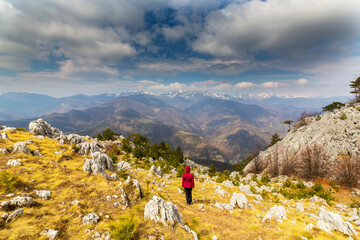 Fototapeta premium Beautiful scenery in the mountains with sharp limestome rocks, hiking path and April sky and showers, with cumulus clouds