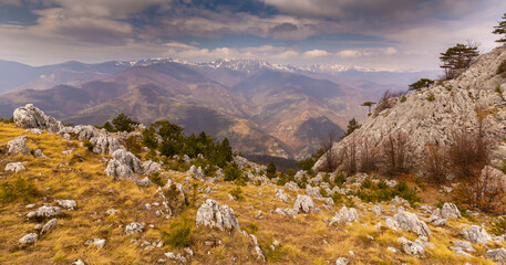 Beautiful scenery in the mountains with sharp limestome rocks, hiking path and April sky and showers, with cumulus clouds