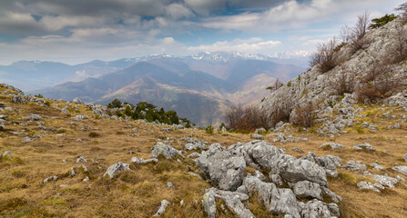 Beautiful scenery in the mountains with sharp limestome rocks, hiking path and April sky and showers, with cumulus clouds