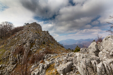 Beautiful scenery in the mountains with sharp limestome rocks, hiking path and April sky and showers, with cumulus clouds
