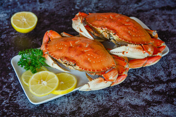 Two boiled crabs with lemon and parsley on a white plate.   © Olga