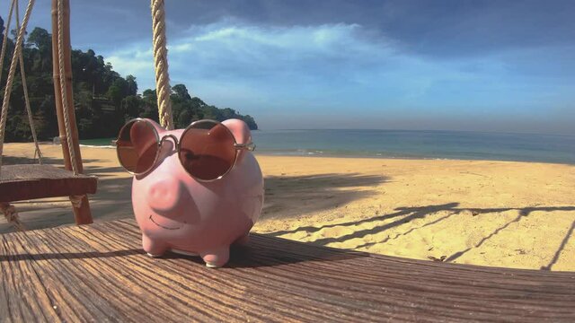 Pink piggyback relaxing on a swing beachfront with blue sky background in summer season. Travel to southern beach. Saving money for vacation when still younger.Lifestyle of health people.