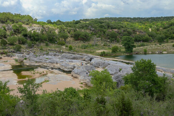 Fototapeta na wymiar Views of the Pedernales river with a natural stone levee formation creating geological rock poos located at the Pedernales Falls State Park in Texas part of the Central Texas Hill Country