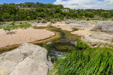 The Pedernales river tributaries trickle through the dry riverbed flowing along the sandstone rock...