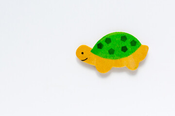 Wooden flat small turtle on an isolated white background. Children's educational green figurine made of wood with a copyspace. Top view, flat lay. Bright hand-made funny toy for a baby for collage.