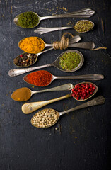 Various spices spoons on black table. Top view with copy space