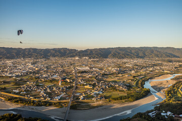 和歌山県紀の川市の竹房橋上空を飛ぶパラグライダーを空撮