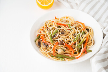 Noodles with vegetables (string beans, bell peppers, sesame seeds) and mushrooms in soy sauce, traditional Asian food