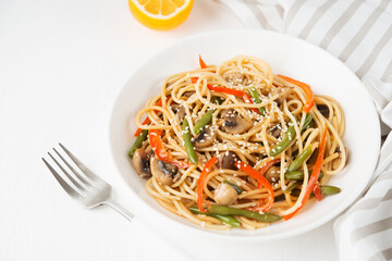 Noodles with vegetables (string beans, bell peppers, sesame seeds) and mushrooms in soy sauce, traditional Asian food