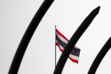 Thai flag through the fence on white sky background