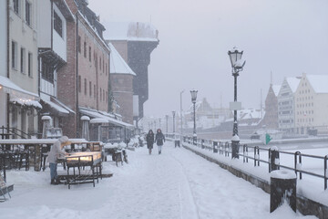 Motlawa in Gdansk Old Town in a snowy blizzard. Silhouettes of people on the street. Poland