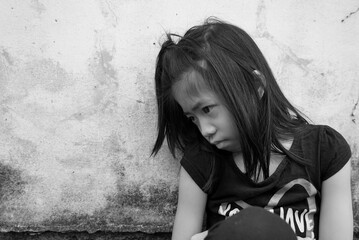Depressed 7 years old Asian little girl sitting alone on dirty floor. Copy space. Kid with attention deficit hyperactivity disorder (ADHD) can not handle her emotion.